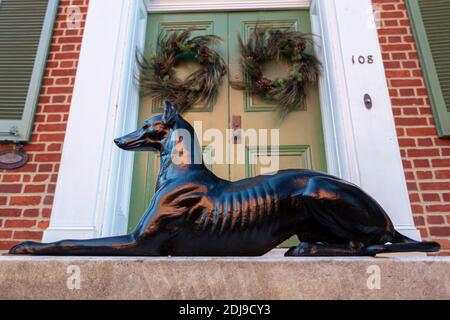 Frederick, MD, USA 12-02-2020: Un modèle de chien noir brillant décoratif mis devant la porte d'entrée en bois d'un bâtiment historique en brique dans la vieille ville. T Banque D'Images