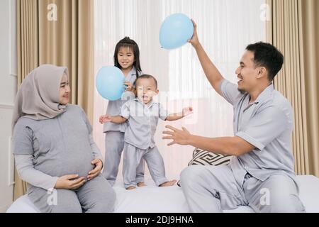 Portrait de famille heureux en vêtements de piyama jouant des ballons ensemble. Concept de photo de famille dans la chambre Banque D'Images