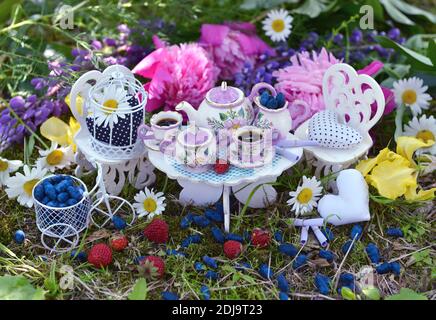 Mad Tea Party concept avec petit mobilier décoré, tasses, théière et fleurs. Alice au pays des merveilles Banque D'Images