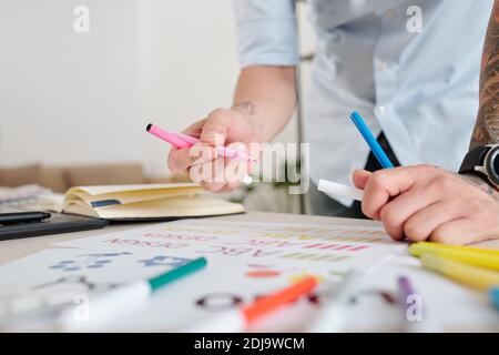 Image en gros plan des croquis de dessin de graphiste du logo de la société avec des stylos à pointe feutre colorés Banque D'Images