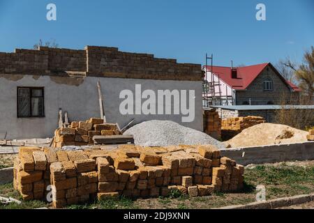 Une pile de briques se trouve devant la maison en cours de construction. Banque D'Images