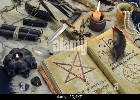 Encore la vie avec la magie noire livre de grimoire, des bougies de combustion et des objets rituels sur table de sorcière. Arrière-plan ésotérique, gothique et occulte, Halloween mystique Banque D'Images