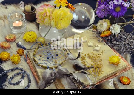 Encore la vie avec vieux livre de journal, runes, dreamcatcher, bougie et objets magiques rituels sur table de sorcière. Arrière-plan ésotérique, gothique et occulte, Halloween Banque D'Images