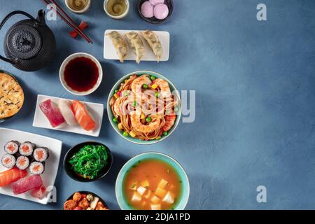 Cuisine japonaise variée avec espace de copie. Divers plats orientaux, tournés depuis le haut avec un espace de copie sur fond bleu Banque D'Images