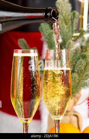 Robe Père Noël adulte verser du champagne. Verser du vin mousseux par des verres, célébration, début des vacances, concept de succès Banque D'Images