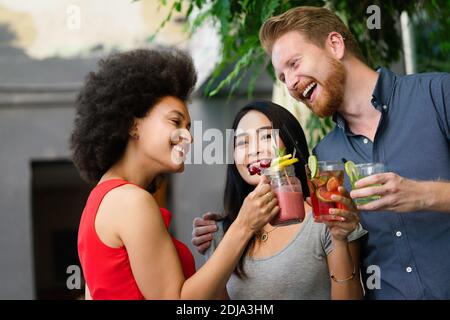 Un groupe diversifié d'amis heureux s'amuser, parler dans un café en plein air en été Banque D'Images