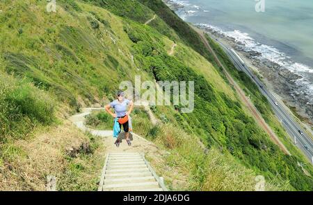 Une femme (61) fait une pause sur une section abrupte de la piste d'escarpement de Paekakariki, Île du Nord en Nouvelle-Zélande Banque D'Images