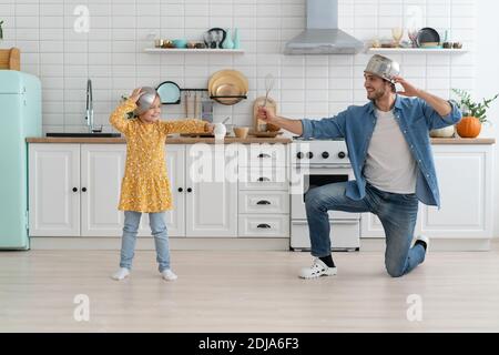 Le père et la fille caucasiens aiment la bataille drôle d'activité dans la cuisine passez du temps actif ensemble le week-end à la maison Banque D'Images