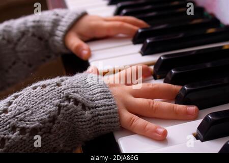 mains d'une petite fille essayant de jouer de la musique de piano Banque D'Images