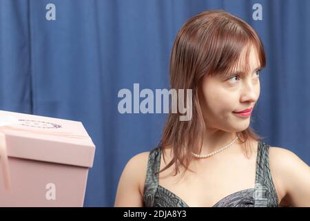 mignonne jeune fille à poil brun déçu d'un cadeau dans un boîte rose sur fond bleu Banque D'Images