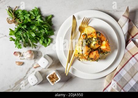 Plat de petit déjeuner italien ou strata d'épinards, fromage et pain de nuit trempé cuit avec de la moutarde sur une assiette blanche avec des couverts dorés sur un Banque D'Images