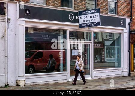 Une femme qui passe devant un magasin vide à laisser à Chichester. Banque D'Images