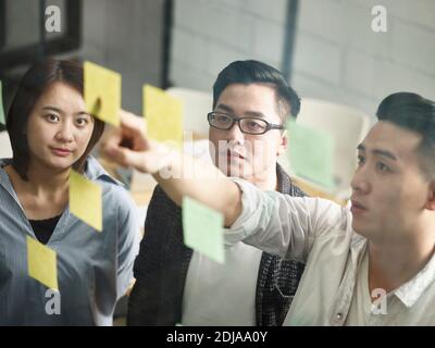 trois jeunes entrepreneurs asiatiques se réunissent au bureau pour discuter de leurs affaires Banque D'Images