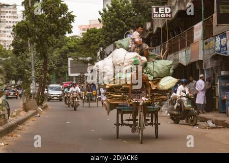 Dhaka, Bangladesh - 30 octobre 2018 : un conducteur de chariot avec une énorme cargaison et un homme au sommet Banque D'Images