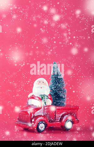 Le Père Noël sur un jouet de voiture rouge avec un arbre de Noël sur fond rouge et de la neige. Célébration de Noël et nouveau concept de fond de l'année, espace copie. Banque D'Images