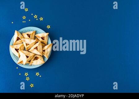 Biscuits ou biscuits Jewish Purim Hamantaschen. Pâtisserie traditionnelle maison pour les fêtes de carnaval des pourim juifs sur fond bleu. Banque D'Images