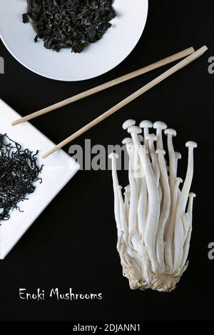 Composition artistique des produits alimentaires asiatiques - champignons Enoki et algues sèches sur fond noir. Déjeuner végétarien. Une alimentation saine. Promotion de concept Banque D'Images