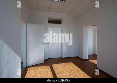 Intérieur moderne d'une salle de bureau vide. Murs et portes blancs. Lumière du soleil sur le sol. Banque D'Images