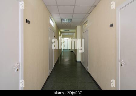 Intérieur moderne d'un couloir étroit dans un immeuble de bureaux. Beaucoup de portes blanches fermées. Banque D'Images