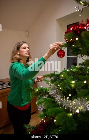 Famille à la maison décorant leur arbre de Noël avant la période de fête de Noël, Royaume-Uni Banque D'Images