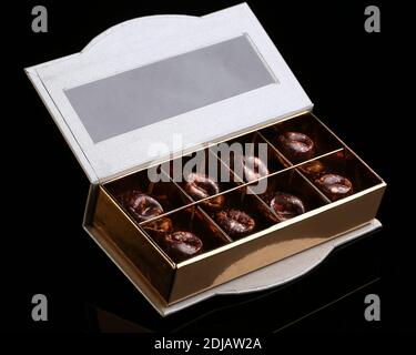 Des bonbons faits main de luxe peints dans une boîte cadeau sur fond noir. Chocolats pour la Saint-Valentin. Banque D'Images