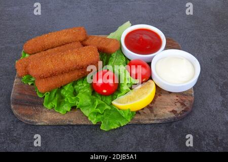 Les doigts de poisson se collent sur une planche en bois, sur une surface en pierre Banque D'Images