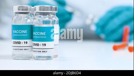 Gros plan des mains de médecin de sexe féminin dans des gants médicaux bleus avec flacon de vaccin liquide transparent contre le coronavirus SARS-COV-2 et seringue pour injection en laboratoire. Recherche et développement d'un nouveau traitement pour les maladies Banque D'Images