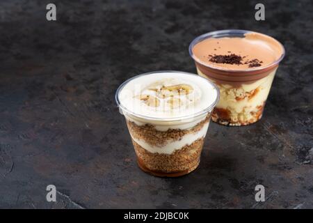 Livraison rapide de nourriture. Dessert à la banane dans une tasse avec banane fraîche sur fond de bois, mise au point sélective, espace de copie, boîte de Takeaway Banque D'Images