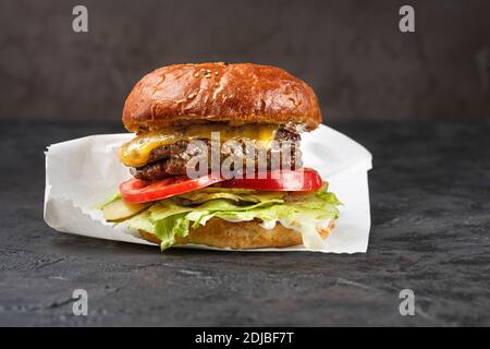 Cheeseburger avec de la viande grillée, du fromage, de la tomate et des pommes de terre sur une surface en pierre sombre. Idéal pour la publicité. Gros plan pour le menu Banque D'Images
