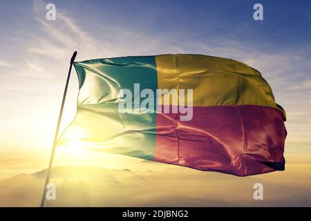 Drapeau du Bénin agitant sur le brouillard de lever de soleil supérieur Banque D'Images