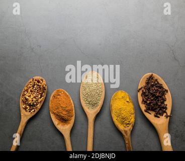 différentes épices sur des cuillères en bois, sur une table grise avec espace pour les copies Banque D'Images