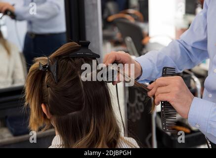 Femme, cliente, ayant ses cheveux coupés dans un salon de coiffure. Cheveux de longueur moyenne avec un lisseur Banque D'Images