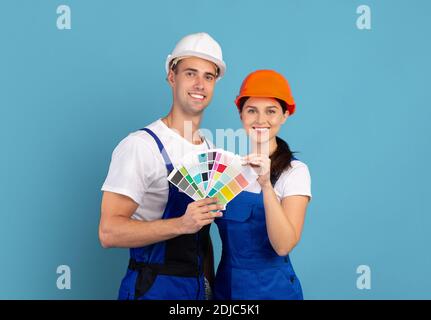 Décorateurs homme et femme en casques de sécurité portant des échantillons de couleur, prêts à être réparés Banque D'Images