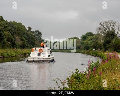 People on a pleasure boat watch a dog retrieving a ball from the Caledonian Canal near Inverness, Highland, Scotland Stock Photo