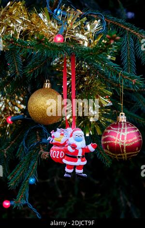 père noël portant un masque décoratif suspendu sur l'arbre de noël au cours de la pandémie du coronavirus 2020 Banque D'Images