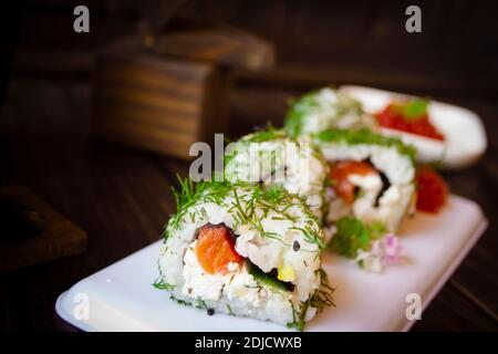 Sushis maki verts. Rouleau de saumon fumé, fromage à la crème et concombre à l'intérieur. Banque D'Images