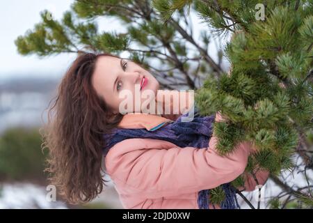 Portrait d'une femme mignonne avec des cheveux longs bouclés et des lèvres rouges, vêtus d'une veste beige et d'une écharpe bleue. La jeune femme caucasienne pose Banque D'Images