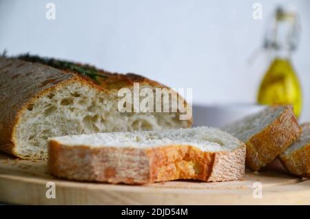 Tranches de pain Ciabatta et romarin sur bois sur fond blanc. Banque D'Images