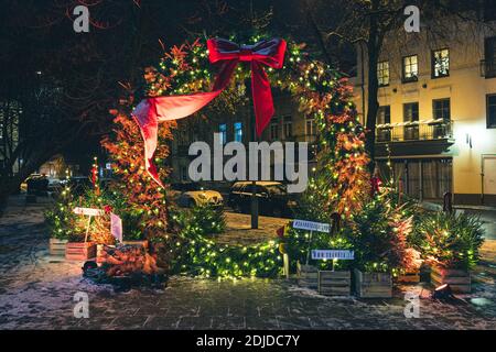 Belles décorations de Noël à Vilnius, Lituanie, avec couronne, ruban rouge, arbres de Noël, lumières et fond de nuit de ville avec neige Banque D'Images