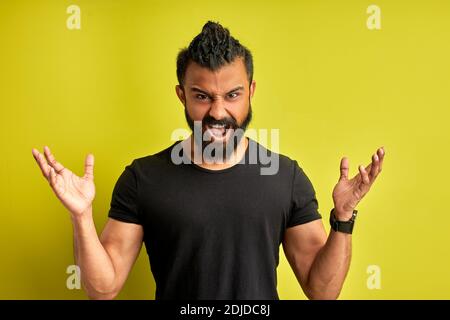un homme barbu en colère hurle à l'appareil photo isolé sur fond vert, le beau homme arabe est irrité Banque D'Images