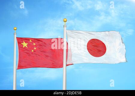 Chine et Japon deux drapeaux sur les mâts de drapeaux et bleu nuageux ciel Banque D'Images