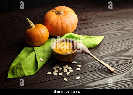 Bol avec soupe de potiron et citrouilles fraîches sur fond de table en bois rustique foncé. Banque D'Images