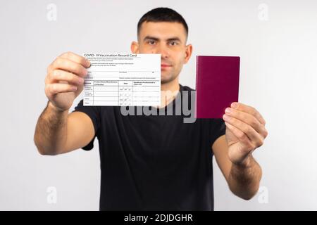 Homme caucasien avec une carte de vaccination et un passeport dans ses mains. Le concept des conditions pour quitter le pays en pandémie. Photo de haute qualité Banque D'Images