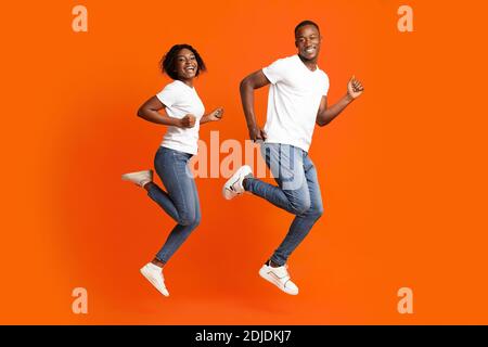 Couple afro-américain aimant en train de courir dans les airs, photo en studio Banque D'Images