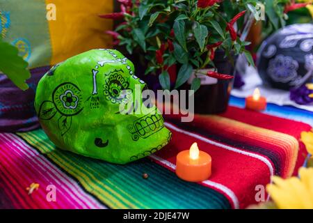 Foyer sélectif de bougie lumineuse et électrique, et décoré de sucre vert crâne sur tissu avec piment rouge frais à l'occasion de la célébration de dia de los muertos Banque D'Images