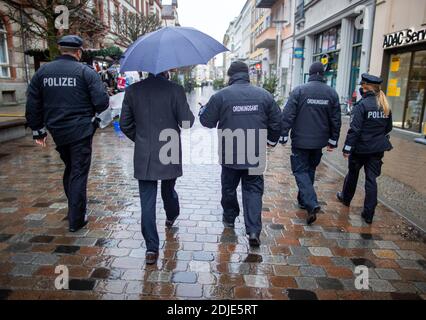 14 décembre 2020, Mecklembourg-Poméranie occidentale, Schwerin: Torsten Renz (CDU, 2e à partir de la gauche), ministre de l'intérieur de Mecklembourg-Poméranie occidentale, accompagne les policiers et les employés du bureau de l'ordre public lors d'une visite d'inspection pour vérifier si l'obligation de porter des masques est observée dans le centre-ville. Le bureau de l'ordre public et la police patrouillent dans les centres urbains et surveillent les mesures de protection de la couronne. Deux jours avant la fermeture d'une grande partie du commerce de détail, beaucoup de gens ont profité de lundi pour faire des achats de façon intensive une fois de plus. Les gouvernements fédéral et des États l'ont fait Banque D'Images