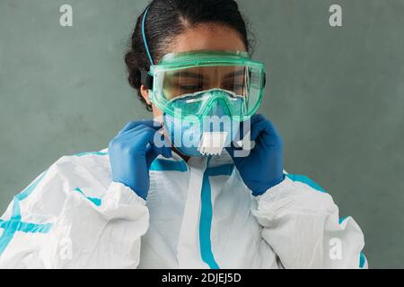 Jeune médecin en lunettes de protection et en costume de masque réglable Banque D'Images