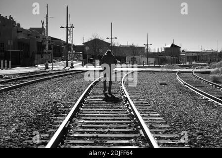 Un homme solitaire marche le long des voies ferrées qui traversent Santa Fe, au Nouveau-Mexique. Banque D'Images