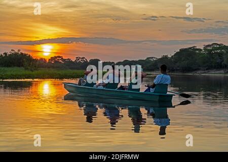 Lever du soleil sur la grande rivière Mutum dans le Pantanal AS un petit groupe de touristes pagayez dans un canoë ouvert Lors d'une excursion tôt le matin pour observer la faune à B Banque D'Images