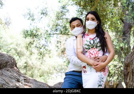 Jeune couple aimant marchant dans des masques médicaux dans le parc pendant la quarantaine. Coronavirus, maladie, protection, malade Banque D'Images